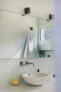 Un baño blanco con lavabo y espejo. en Marea Alta, en La Caleta 11 fotos más
