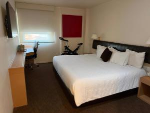 a hotel room with a large bed and a desk at Hotel VM Express Queretaro in Mendiola