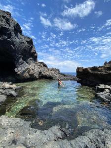 una persona en un cuerpo de agua con rocas en Marea Alta, en La Caleta