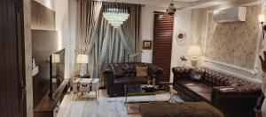 a living room with brown leather furniture and a chandelier at 2 bed Stylish Furnished Apartments at Prime Location in Lahore