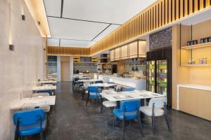 a restaurant with white tables and blue chairs at Fairfield by Marriott Wuhan Hankou in Wuhan