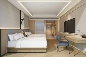 a bedroom with a bed and a desk and a television at Fairfield by Marriott Qingdao West Coast in Qingdao