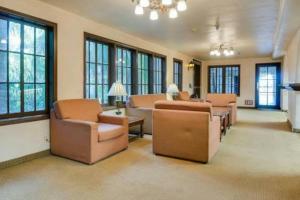 a living room with chairs and a couch and windows at The Buena Park Grand Hotel & Suites in Buena Park