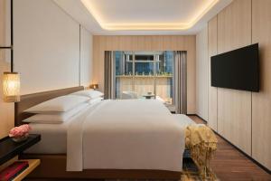 a bedroom with a large white bed and a television at Marriott Executive Apartments Bengaluru UB City in Bengaluru