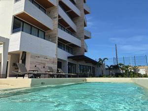 a swimming pool in front of a building at Beachfront 2BR 2BA Condo w Balcony, Ocean Views in Puerto Morelos