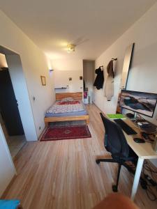 a bedroom with a bed and a desk with a computer at Schönes, zentral gelegenes Zimmer mit Südbalkon in Munich