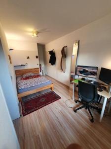 a bedroom with a bed and a desk and a chair at Schönes, zentral gelegenes Zimmer mit Südbalkon in Munich