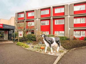 una estatua de una vaca delante de un edificio en ibis Metz Nord, en Woippy