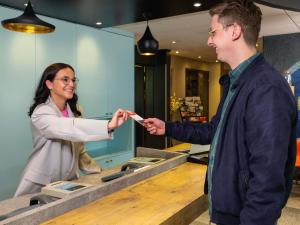 a woman giving a man a cell phone in a store at ibis Metz Nord in Woippy