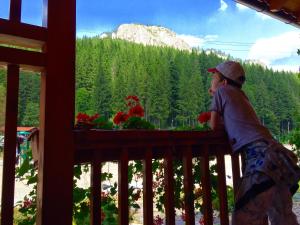 Ein Mann steht auf einem Balkon mit Bergblick. in der Unterkunft Lacu Roșu Mountain Lodge in Lacul Roşu