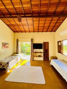 a large room with two beds and a flat screen tv at Family Guest House in Ilha de Boipeba