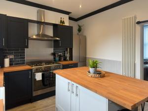 a kitchen with black cabinets and a wooden counter top at Bronte Hideaway in Haworth