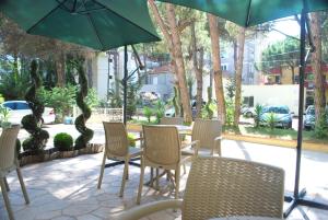 een patio met stoelen en een tafel met een parasol bij Rezidenca Kalter Durres in Golem