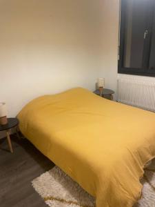 un letto giallo in una stanza con due tavoli di Chambre invididuelle 2 a Millau