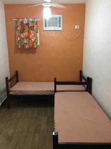 2 letti in una camera con finestra e ventilatore di Chalé Suites Maresias a São Sebastião