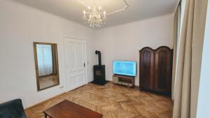 a living room with a television and a chandelier at Villa Ohrenstein - Komfort Suite in Bad Ischl