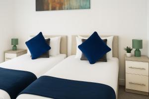 2 camas con almohadas azules en un dormitorio en Flexistay hub at Watford, en Abbots Langley 12 fotos más
