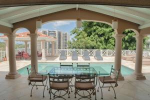 eine Terrasse mit einem Glastisch und Stühlen neben einem Pool in der Unterkunft Villa Marrakesh, Cupecoy Beach - A Luxury Villa with Pool in Lowlands