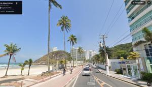 une rue de ville avec des palmiers et une plage dans l'établissement Apartamento Lelis - Descanso para a família e seu pet, pertinho do mar - praia Guarujá - SP, à Guarujá