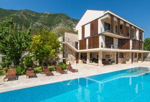 a villa with a swimming pool and a house at Apartments Feral in Kotor