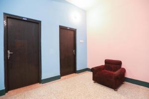ein Raum mit einem roten Stuhl und zwei Türen in der Unterkunft Hotel O PG Guest House in Tangra