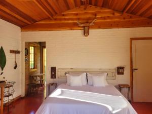 a bedroom with a bed with white sheets and pillows at Cabana Arbosana in São Bento do Sapucaí +12 photos