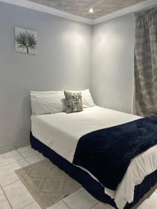 a bedroom with a large bed with a blue blanket at Amza guest room in Mogwase