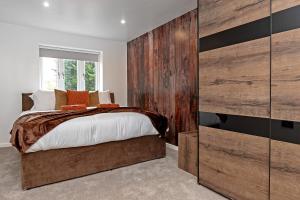 a bedroom with a bed and a wooden wall at Contractors Heaven-POOL TABLE-THREE BEDROOM HOUSE WITH SEPARATE ONE BEDROOM SELF CONTAINED-Close to AIRPORT in Luton
