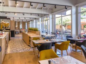a restaurant with tables and chairs and windows at Novotel Narbonne Sud A9/A61 in Narbonne