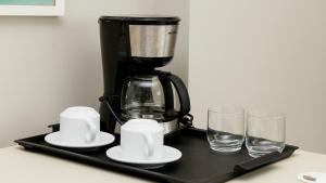 レシフェにあるPaiva Home Stay - Flat Beira-Mar em Barra de Jangada por Yoloの黒いトレイの上にコーヒーメーカーとグラス2つ