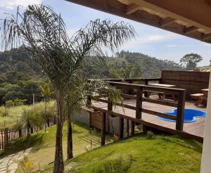 a house with a palm tree on a deck at Chalé Recanto do Pimenta e Casa Recanto do Pimenta in Pedra Azul