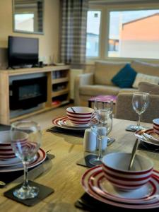 a wooden table with plates and wine glasses on it at Birchington Vale Trieste - Sleeps 8, pet friendly & Family friendly in Birchington
