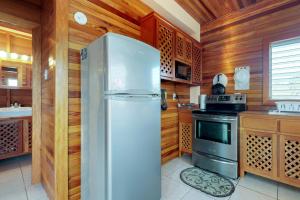 a stainless steel refrigerator in a kitchen with wooden walls at Loft at Roughrider Inn -Gold Standard Certified in Caye Caulker +19 photos