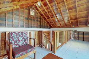 a room with a chair in a room with wooden ceilings at Loft at Roughrider Inn -Gold Standard Certified in Caye Caulker