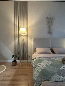 a bedroom with a bed and a floor lamp at Уютная квартира 5 минут от Барыс арены in Astana