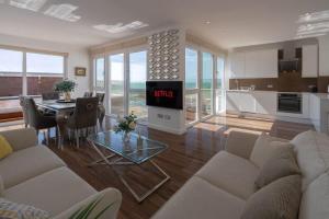 ブライトン＆ホーブにあるOn The Beach Penthouse with Sea View - 3 bedrooms - Roof Terrace - Spa, Sauna, Gym and Pool - Sleeps 6のリビングルーム(ソファ、時計付きテーブル付)
