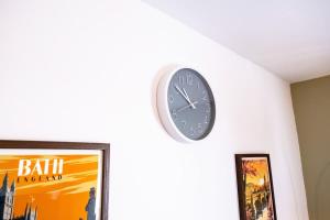 a clock on a wall next to a picture at Ruskin Apartment near Bath - Free Parking - 1 Bedroom - Sleeps 3 in Midsomer Norton