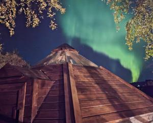 an old wooden boat with the aurora in the sky at The Perfect Stop - Aurora Lodge in Lødingen