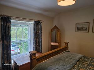 a bedroom with a bed and a window and a mirror at Blea Tarn Farmhouse B&B in Ambleside