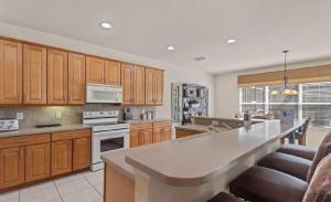 Una gran cocina con gabinetes de madera y una gran isla. en Luxurious 5BR Watersong Resort Villa | Private South-Facing Pool and Spa, en Loughman