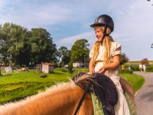 a young girl riding on the back of a horse at Wellness woning met sauna in Andijk +2 photos