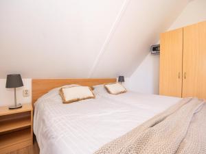 Un dormitorio con una cama blanca y un armario de madera. en Villa in Andijk with South-Facing Garden, en Andijk 15 fotos más