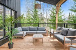 a patio with couches and a table on a deck at Oasis et Spa du Capitaine in Peribonka