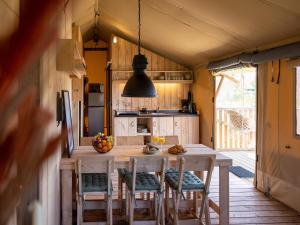 a kitchen with a table and chairs in a house at Safari Lodge near IJsselmeer Glamping in Andijk +5 photos