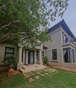 a large white house with a tree in the yard at Potch Manor Boutique Guest House in Potchefstroom
