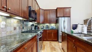 a kitchen with wooden cabinets and a stainless steel refrigerator at Red Slate Canyon - Modern 2-Story Condo in Mammoth Lakes