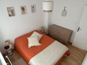 a bedroom with a bed with an orange and white pillow at Aux flots d AuRa in Grand-Fort-Philippe