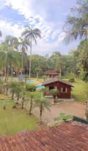 a small house with palm trees and a pool at Espaço Villa dos Anjos in Morretes