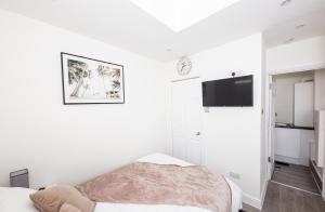 a white bedroom with a bed and a tv at Jayjay Guest House in Basildon