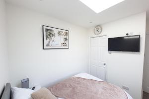 a bedroom with a bed and a tv on the wall at Jayjay Guest House in Basildon